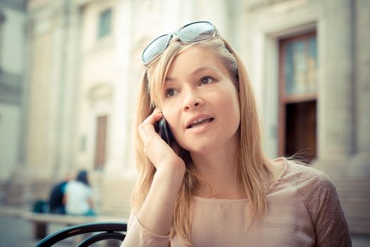 beautiful blonde woman on the phone at the bar in the city