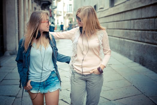 two beautiful blonde women walking and talking in the city