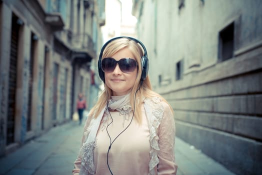 beautiful blonde woman listening to music in the city