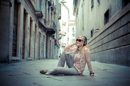 beautiful blonde woman listening to music in the city