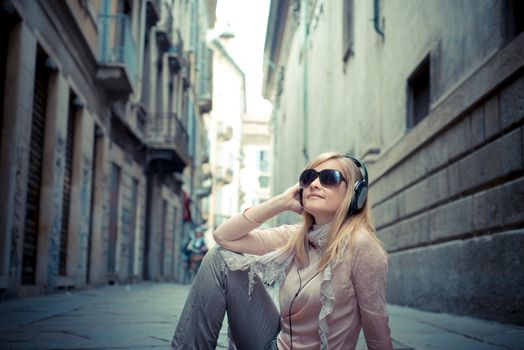 beautiful blonde woman listening to music in the city