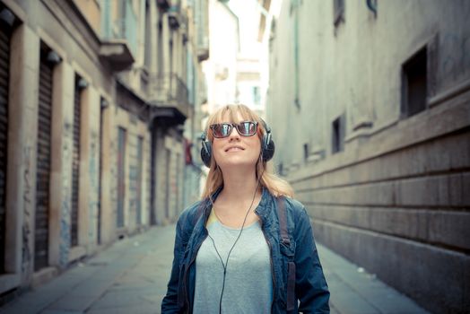 beautiful blonde woman listening to music in the city