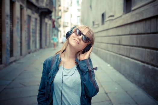 beautiful blonde woman listening to music in the city