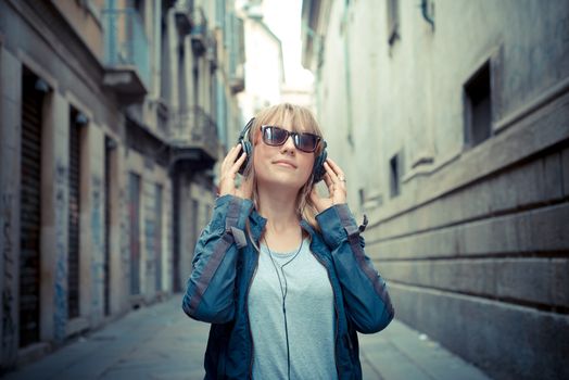 beautiful blonde woman listening to music in the city