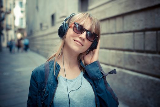 beautiful blonde woman listening to music in the city