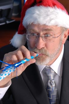 A senior businessman at a Christmas party, wearing a Santa hat and blowing a party blower