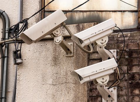 Three Security cameras frontal view on concrete wall