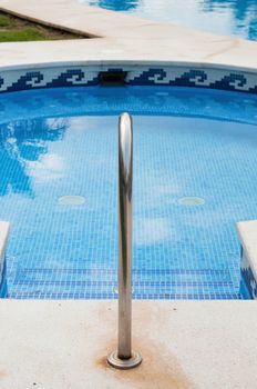 Blue swimming pool with stairs and banister