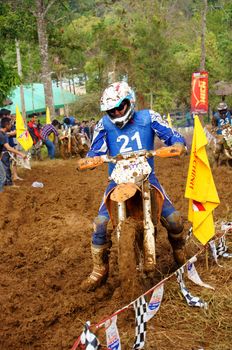 The motorcycle race hole on December at Dambri waterfall, motorcyclist try to speed up goal, red soil way, indistinct dust. December23, 2012