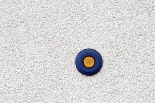 abstract view of blue and yellow button on mortar finished wall