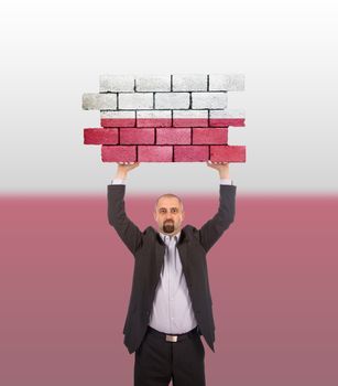 Businessman holding a large piece of a brick wall, flag of Poland, isolated on national flag
