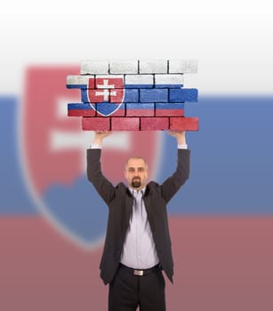 Businessman holding a large piece of a brick wall, flag of Slovakia, isolated on national flag