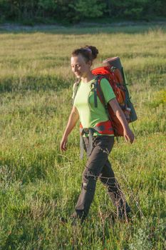 Happy smiling woman in field. Green grass in foreground and clear sky in background.