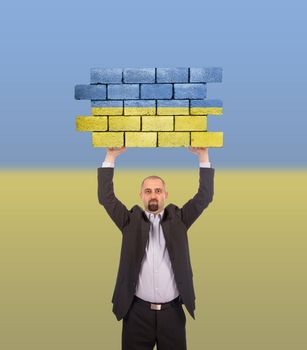 Businessman holding a large piece of a brick wall, flag of Ukraine, isolated on national flag