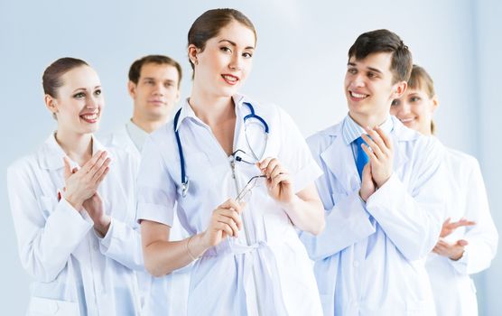 successful doctor, accepts congratulations from colleagues, stand behind him and clap