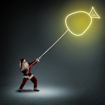 Santa Claus pulls a rope with a symbol bag with a gifts