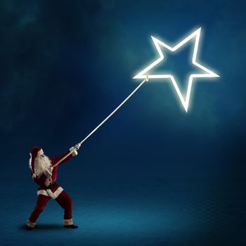 Santa Claus pulls the shining star using a rope