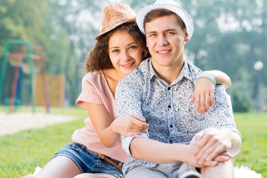 romantic couple lying on the grass in the summer park, spending time with loved ones