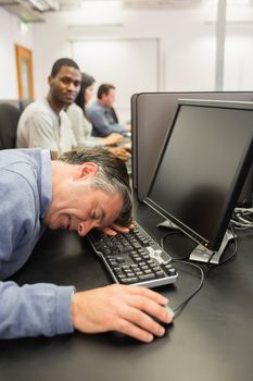 Man taking nap at computer class on the keyboard in college