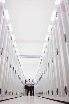 Technicians standing at end of server hallway with arms crossed in data center