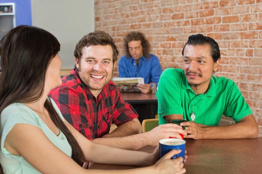 Asian man drinking coffee with Caucasian friends in cafe