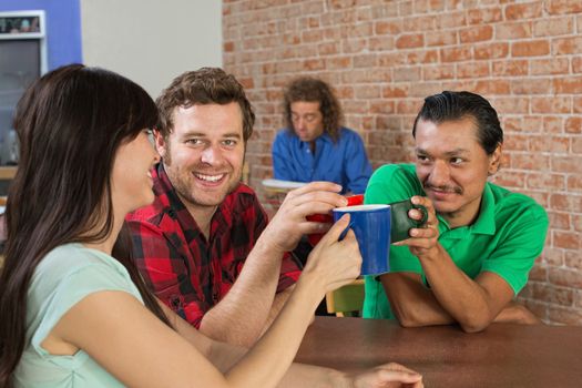Diverse trio of friends toasting with coffee mugs