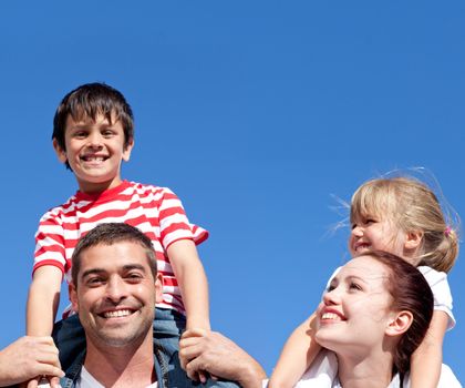 Parents giving their children piggyback ride in front of the sky