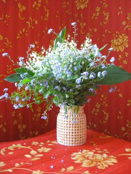 beautiful bouquet of lilies of the valley and blue flowers on a red background