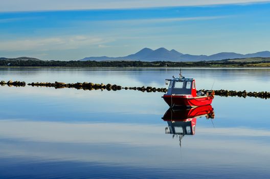 Small red boat in the water of peaceful harbour