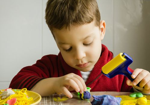 Cute child playing with colorful plasticine in a table