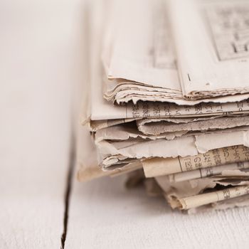 Pile of black and white newspapers on a wooden table