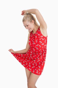 Young woman in red summer dress dancing over white background