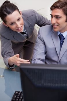 Business man and woman in discussion while using computer at office