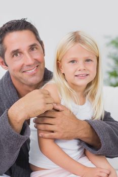 Smiling father hugging his daughter and looking at camera