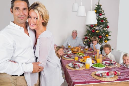Husband and wife embracing beside the dinner table at christmas