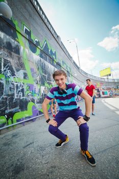 Happy teens boy with his friends by painted wall looking at camera. Vertical view