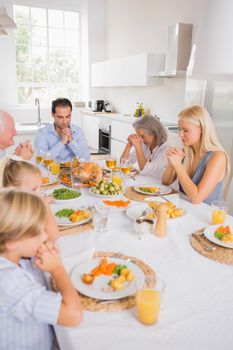 Family praying before eating for thanksgiving