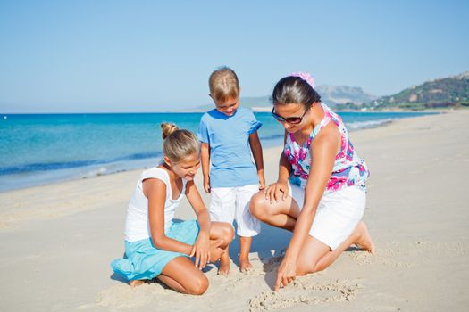 Adorable happy two kids with mother having fun on tropical beach
