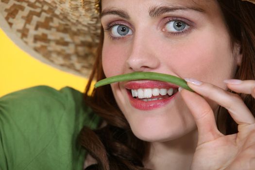 Woman pretending green bean is a mustache