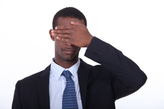 Businessman covering eyes with hand