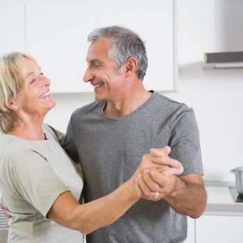 Smiling mature couple dancing together in the kitchen