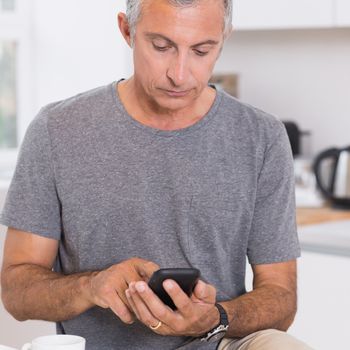 Man touching his smartphone in the kitchen
