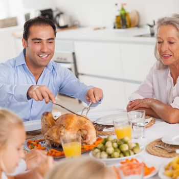 Man carving the thanksgiving turkey at head of table