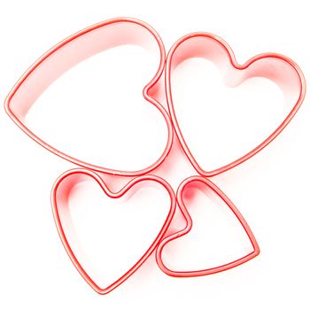 Four pink heart cookie cutters on white background