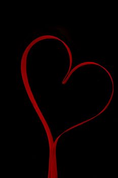 Red heart shaped ribbon on black background