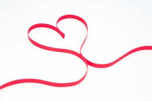 Pink ribbon in heart shape on white background