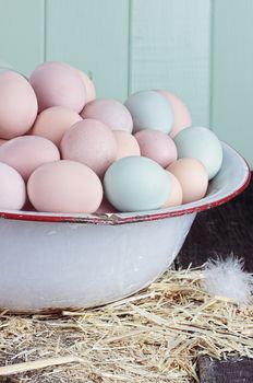 Antique wash pan filled with colorful fresh farm raised eggs against a rustic background.