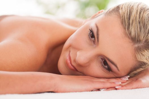 Beautiful caucasian woman with blond hair lying in a spa