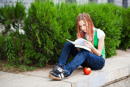 student reading book with apple