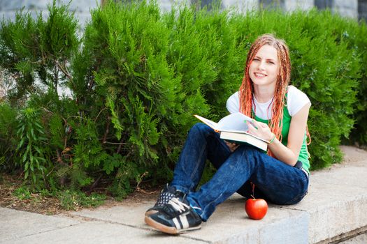 student with books and apple outdoors